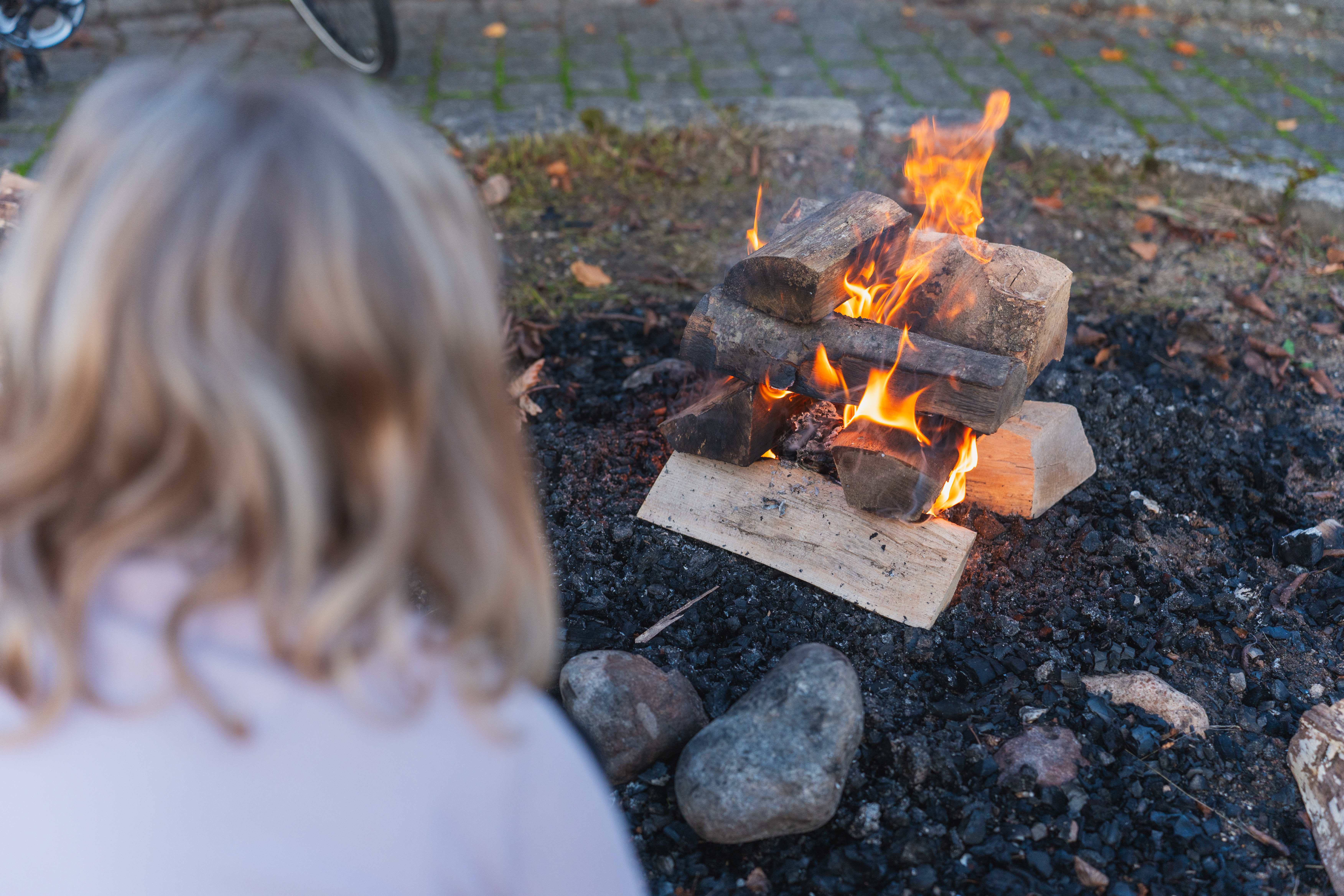 Pige sidder ved bål