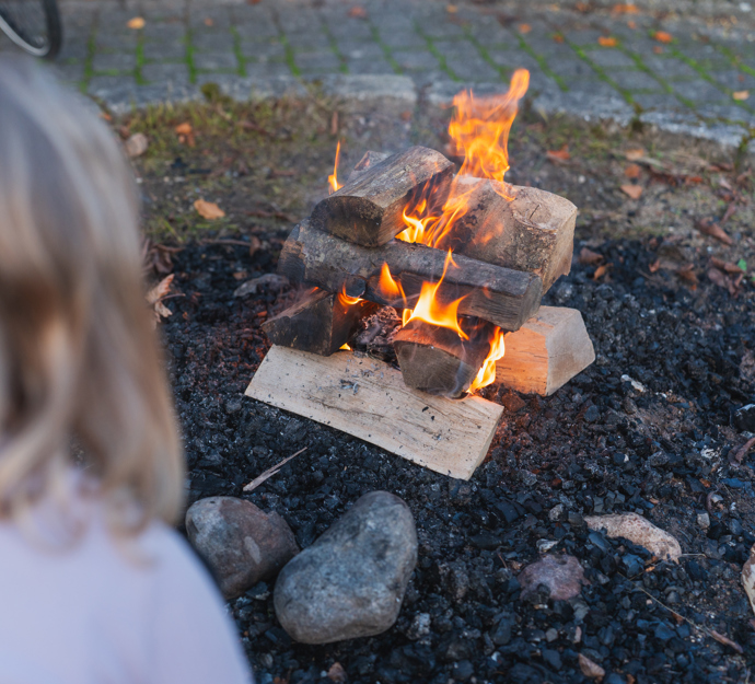 Pige sidder ved bål